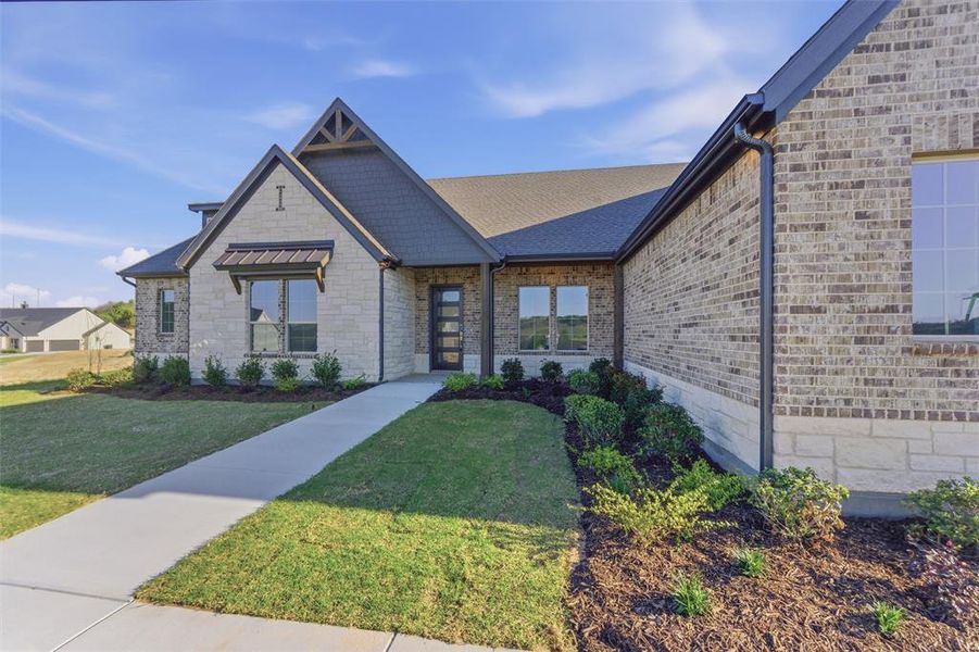 View of front facade with a front yard, stone siding, and brick siding