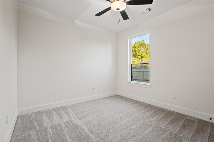 Carpeted empty room featuring baseboards and a ceiling fan