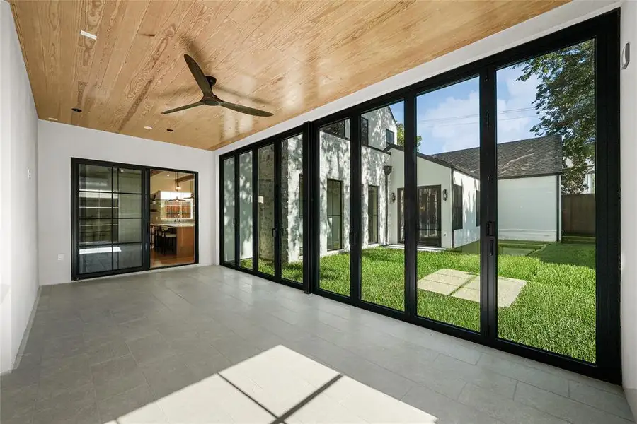 Expansive sunroom featuring wood-finish ceiling, a modern ceiling fan, and light gray tile flooring