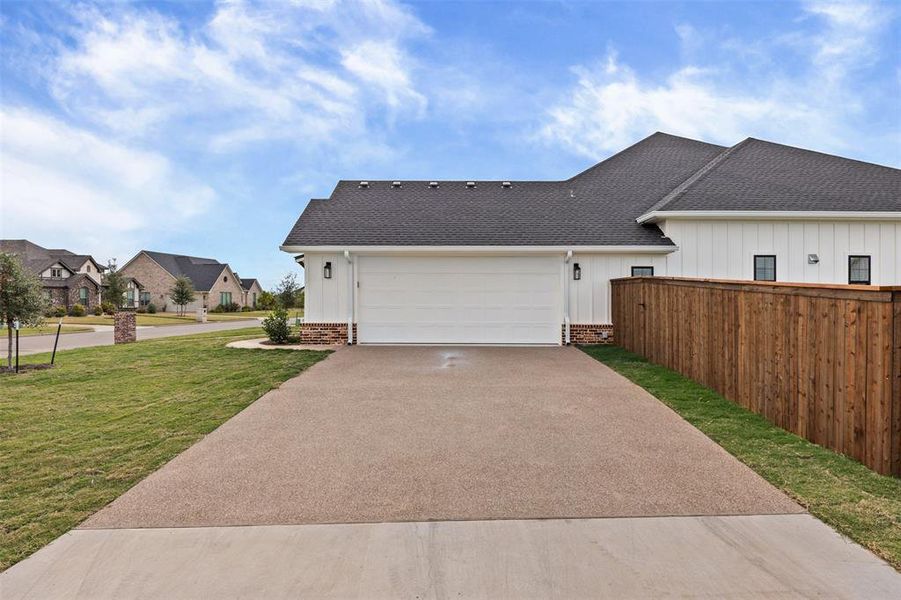 View of side of property with a shingled roof, concrete driveway, an attached garage, and brick siding View of side of property with a shingled roof, concrete driveway, an attached garage, and brick siding