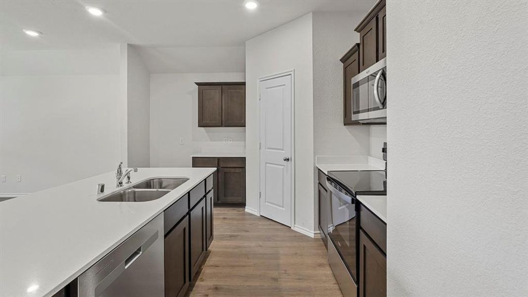 Open-concept kitchen featuring an island with a double basin sink and stainless steel dishwasher