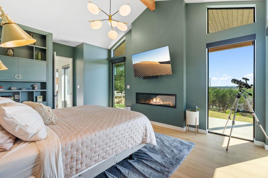 Spacious interior featuring a vaulted ceiling with exposed wood beam, large windows, a built-in linear fireplace, and light wood-finish flooring