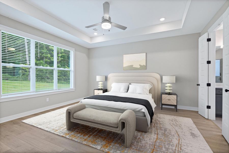 Spacious bedroom featuring wood-finish flooring, a tray ceiling with recessed lighting, and a ceiling fan Spacious bedroom featuring wood-finish flooring, a tray ceiling with recessed lighting, and a ceiling fan