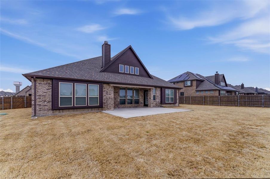 Back of house with a patio area, a chimney, a fenced backyard, roof with shingles, and brick siding