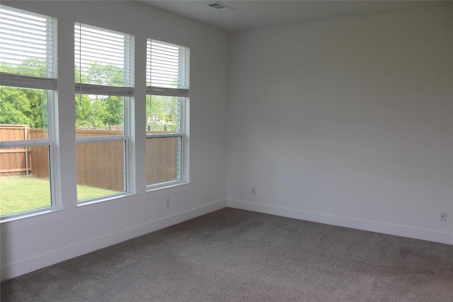 Empty room featuring dark colored carpet and baseboards