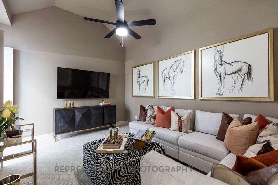 Carpeted living area with vaulted ceiling and a ceiling fan Carpeted living area with vaulted ceiling and a ceiling fan