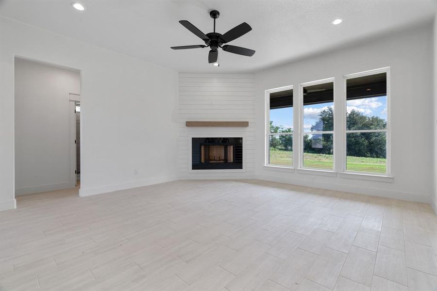 Unfurnished living room featuring a large fireplace, a ceiling fan, recessed lighting, and light wood-type flooring