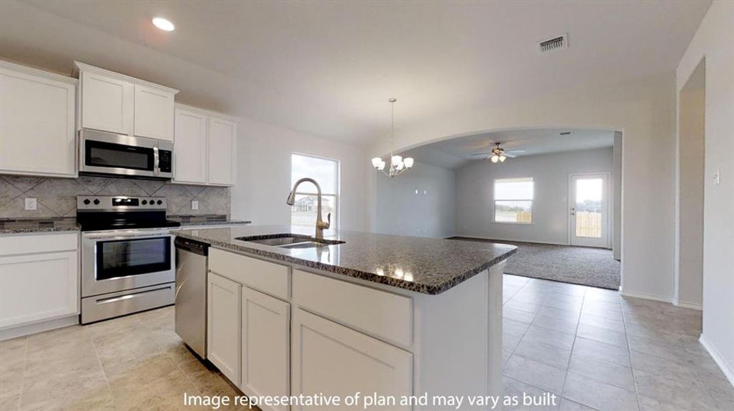 Kitchen featuring stainless steel appliances, a ceiling fan, white cabinets, an island with sink, and decorative backsplash Kitchen featuring stainless steel appliances, a ceiling fan, white cabinets, an island with sink, and decorative backsplash