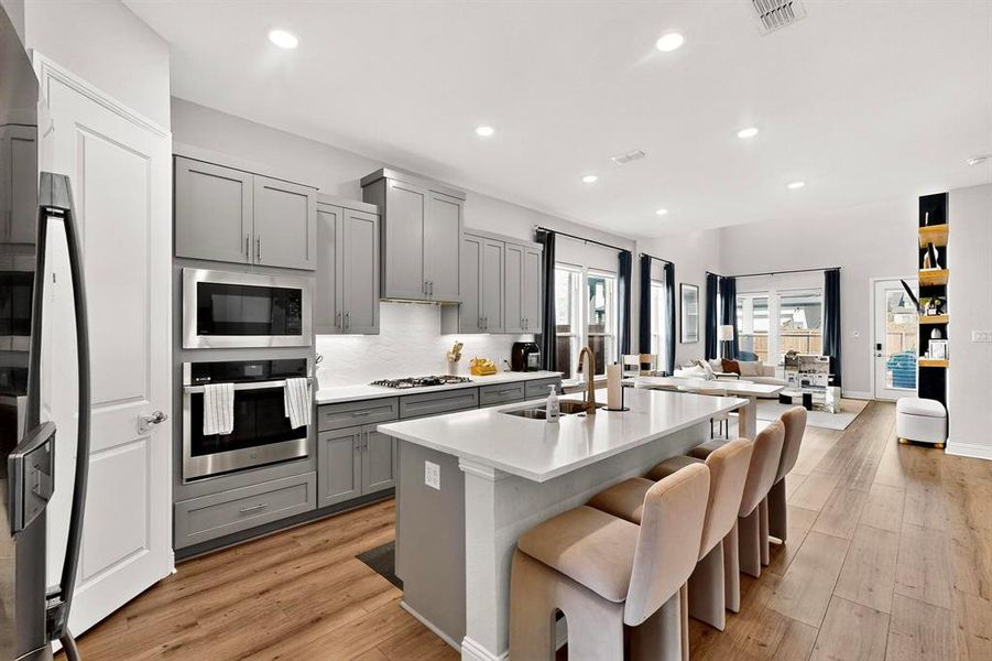 Kitchen with gray cabinets, backsplash, appliances with stainless steel finishes, recessed lighting, and a center island with sink Kitchen with gray cabinets, backsplash, appliances with stainless steel finishes, recessed lighting, and a center island with sink