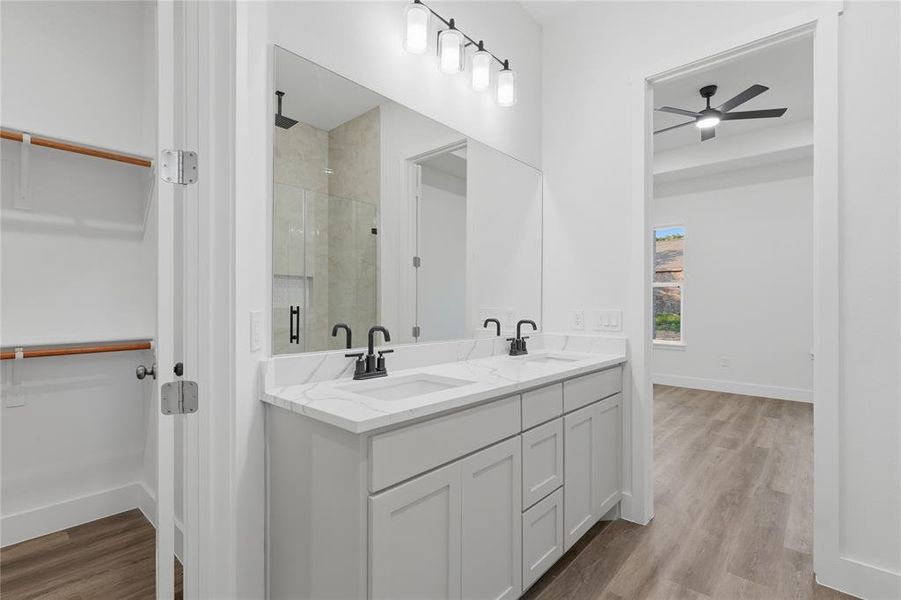 Bathroom featuring a dual vanity with light gray cabinetry and white countertops, matte black hardware, and a large mirror