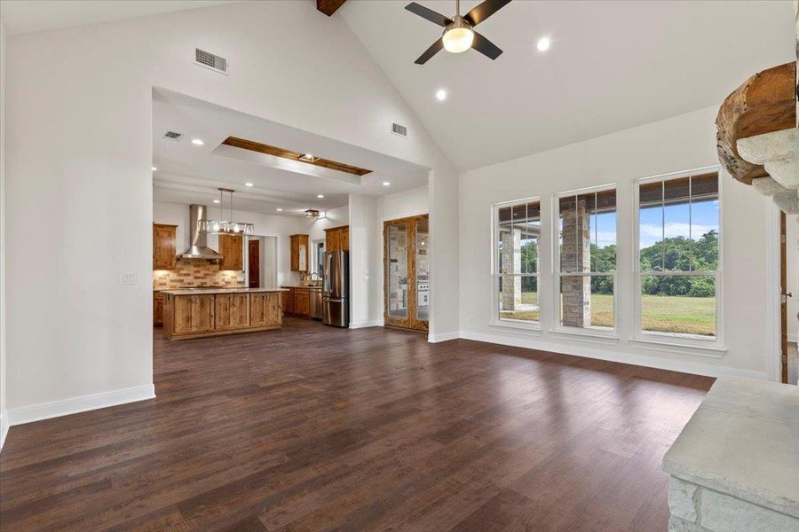 Unfurnished living room with ceiling fan, high vaulted ceiling, dark wood-type flooring, beam ceiling, and recessed lighting