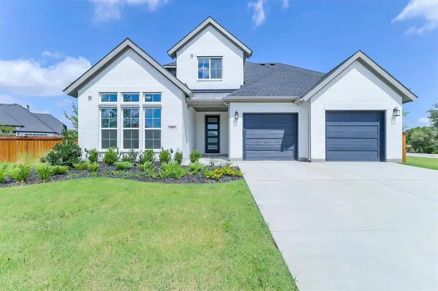 Contemporary white brick exterior with a dark shingle roof, featuring a two-car garage with dark wood-finish doors Contemporary white brick exterior with a dark shingle roof, featuring a two-car garage with dark wood-finish doors