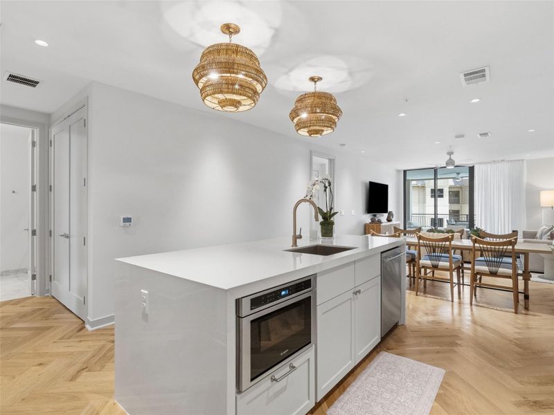 Kitchen island featuring a single-basin sink, integrated drawer style microwave, and white cabinetry Kitchen island featuring a single-basin sink, integrated drawer style microwave, and white cabinetry