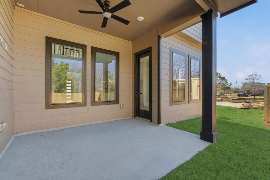 A covered back patio offers a ceiling fan and a conveniently placed outlet—perfect for outdoor TV setup and relaxing.