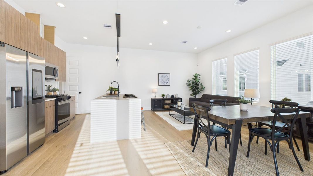 The welcoming second-floor open-concept living area seamlessly combines the living room, dining room, and kitchen, filled with natural light and enhanced by modern finishes and engineered hardwood flooring throughout, creating a bright and inviting space ideal for everyday living and entertaining.