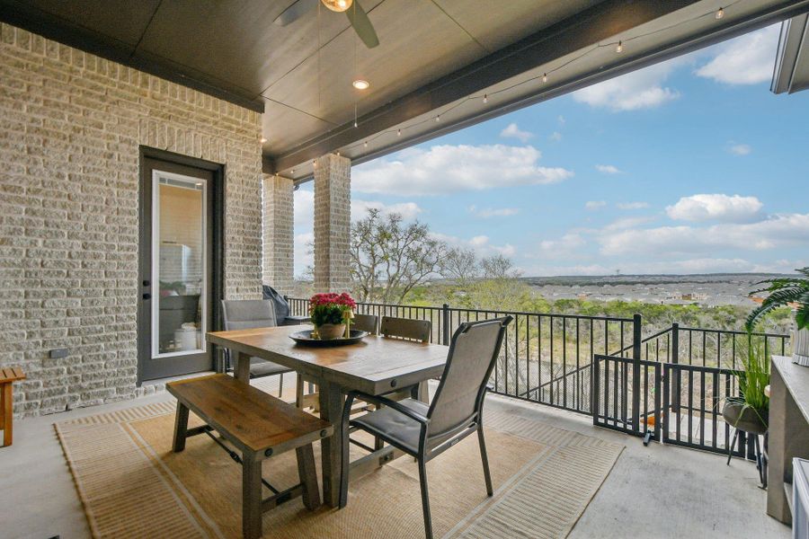 Expansive covered patio featuring brick columns and walls, a ceiling fan, and string lights, with a scenic outdoor view Expansive covered patio featuring brick columns and walls, a ceiling fan, and string lights, with a scenic outdoor view