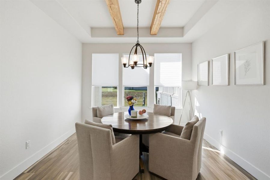 Dining area featuring beam ceiling, plenty of natural light, a chandelier, and light wood-style floors