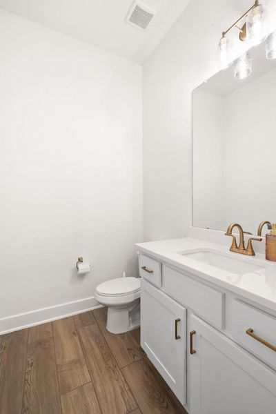 A refined bathroom features wood flooring and a classic vanity with a gleaming mirror.