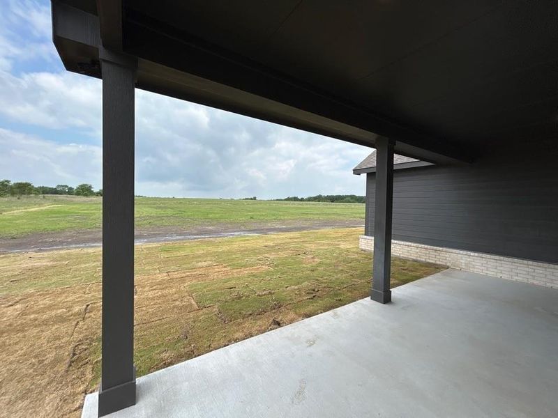 Covered patio featuring a concrete slab, dark pillars, and dark overhead soffit