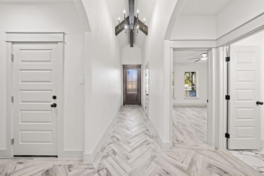 Foyer featuring a chandelier, arched walkways, beam ceiling, parquet flooring, and high vaulted ceiling Foyer featuring a chandelier, arched walkways, beam ceiling, parquet flooring, and high vaulted ceiling