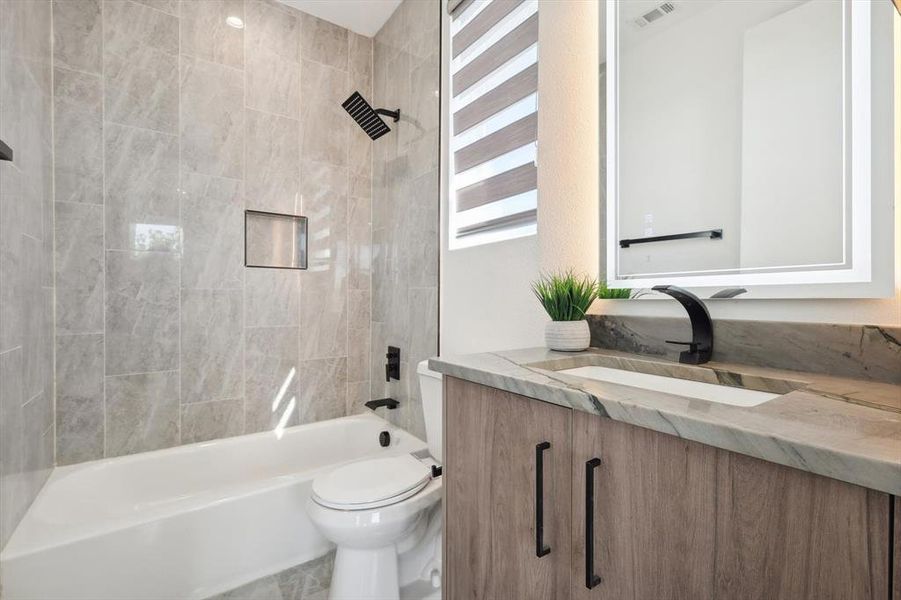 Full bathroom with toilet, vanity, and tiled shower / bath