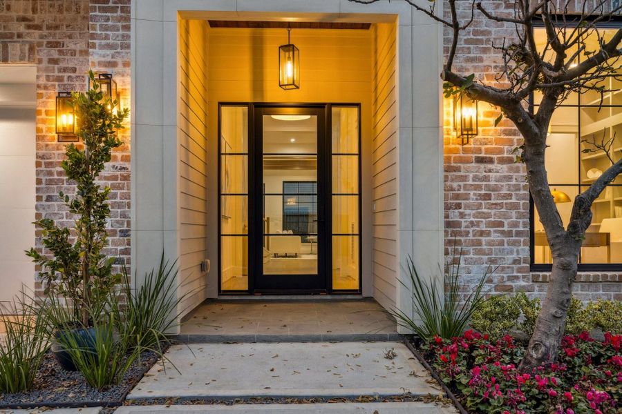 A closer view of the entrance of the home with a Covered Porch, Cast Stone Surround, Tile, Stained Wood Ceiling, Landscaping with full drainage and irrigation. Steel Frame Anderson front door with Sidelights.