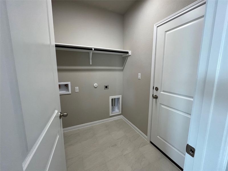 Functional utility space features durable tile flooring and overhead shelving. Functional utility space features durable tile flooring and overhead shelving.