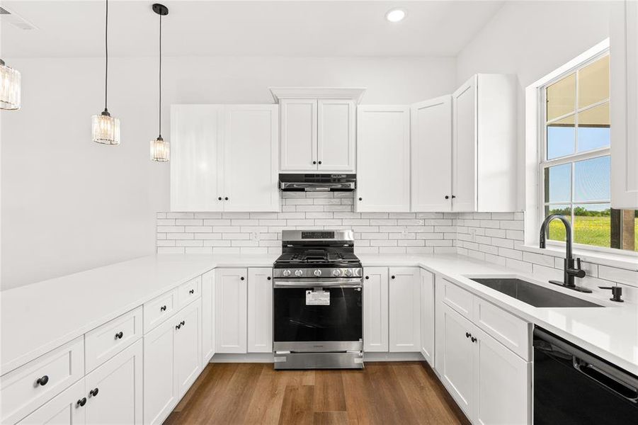 Modern kitchen featuring white shaker cabinetry, stainless steel appliances, white subway tile backsplash, white countertops, and wood-finish flooring