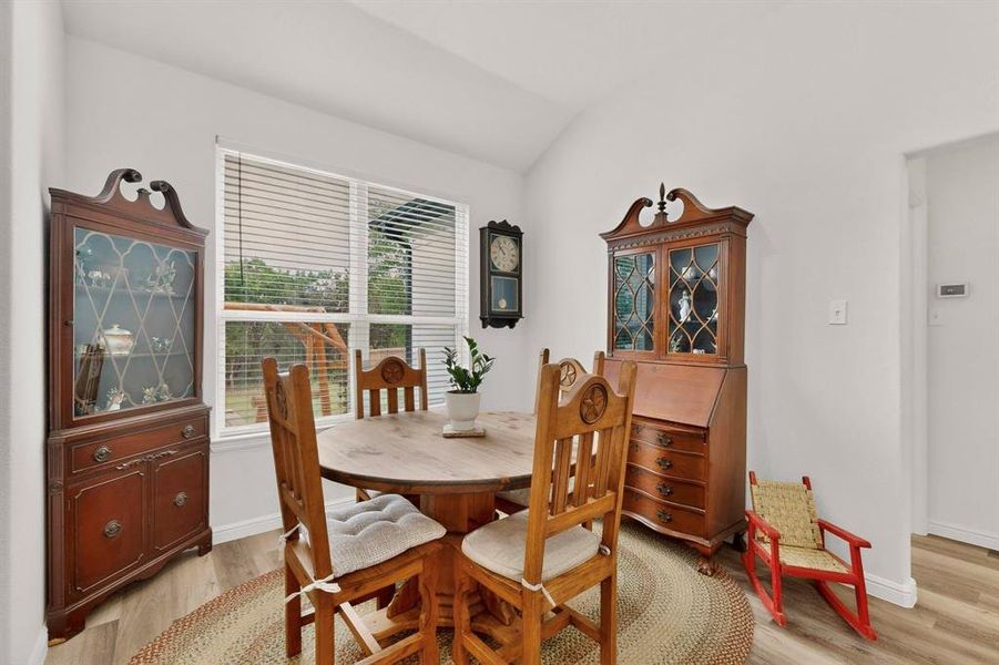 Dining area featuring light wood-finish flooring, white walls, and a large window with horizontal blinds