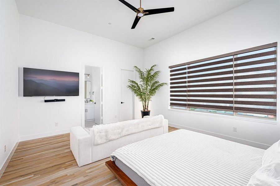 Bedroom featuring ceiling fan, connected bathroom, and light hardwood / wood-style flooring