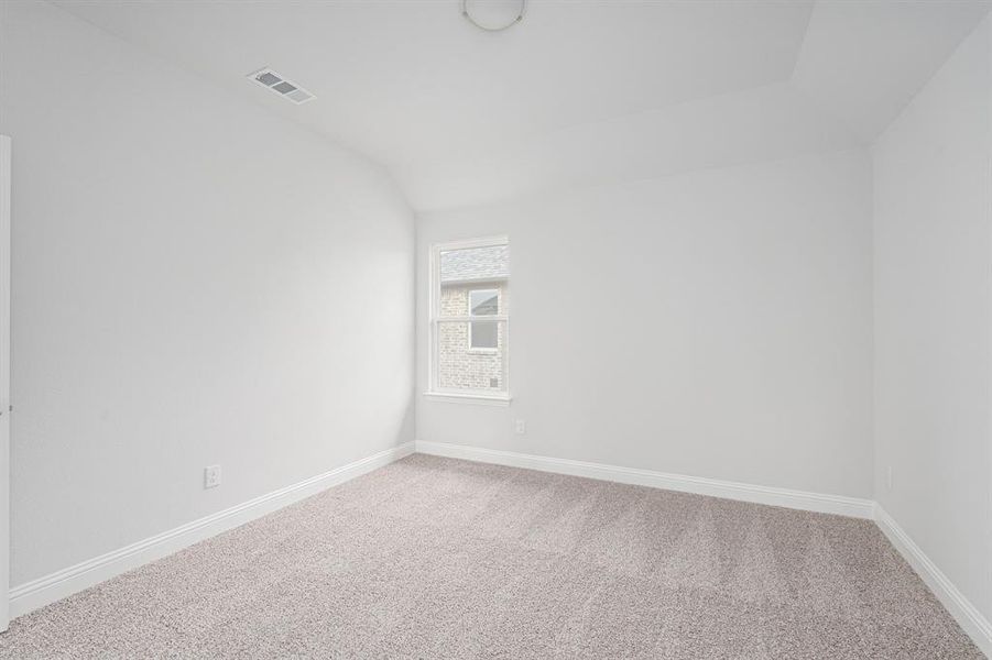 Empty room featuring carpet floors, baseboards, visible vents, and lofted ceiling