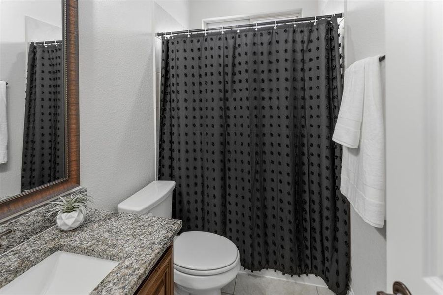 Full bath featuring vanity, a shower with curtain, light tile patterned flooring, and a textured wall