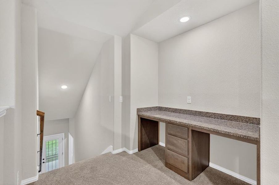 Built-in desk area featuring a speckled countertop and wood-finish cabinetry with drawers Built-in desk area featuring a speckled countertop and wood-finish cabinetry with drawers