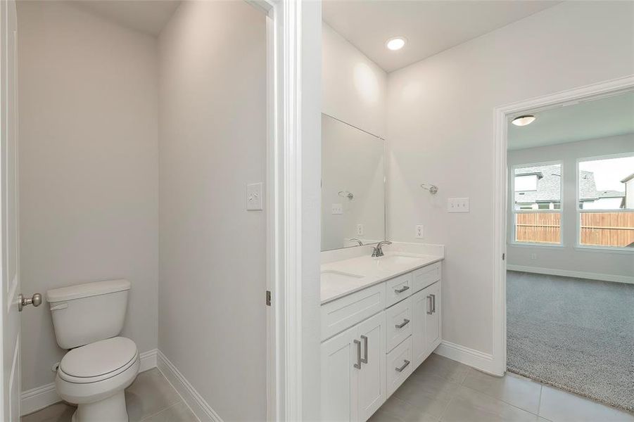 Bathroom featuring baseboards, toilet, tile patterned floors, double vanity, and recessed lighting Bathroom featuring baseboards, toilet, tile patterned floors, double vanity, and recessed lighting