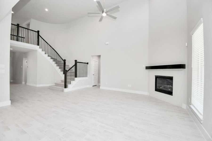 Relax and unwind in this inviting family room, illuminated by abundant natural light streaming in through tall windows, complemented by high ceilings and stunning flooring. Stay comfortable year-round with the gentle breeze from the ceiling fan, creating the perfect atmosphere for family gatherings. Sample photo of completed home with similar floor plan. Actual colors and selections may vary.