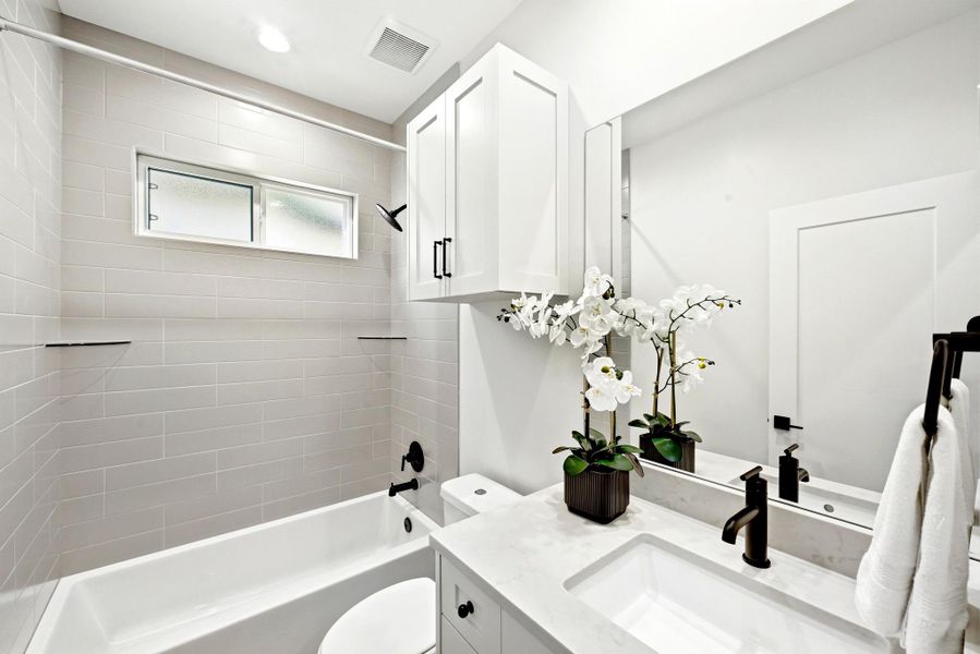 A well-appointed bathroom offers sleek subway tile surrounding the tub, complemented by a modern vanity with ample storage. A well-appointed bathroom offers sleek subway tile surrounding the tub, complemented by a modern vanity with ample storage.