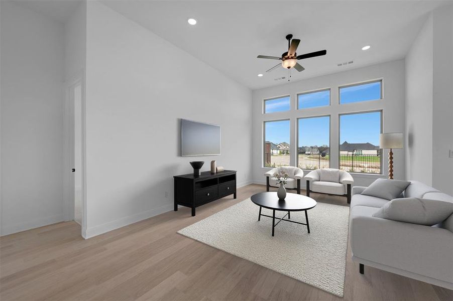 Living room featuring a high ceiling, light wood-type flooring, a ceiling fan, and recessed lighting