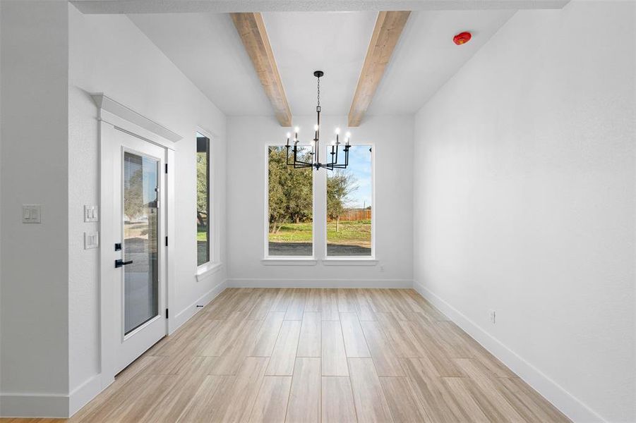 Unfurnished dining area featuring an inviting chandelier and beam ceiling