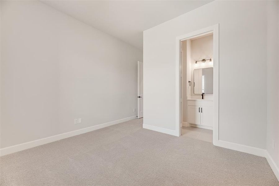 Unfurnished bedroom with light colored carpet and connected bathroom