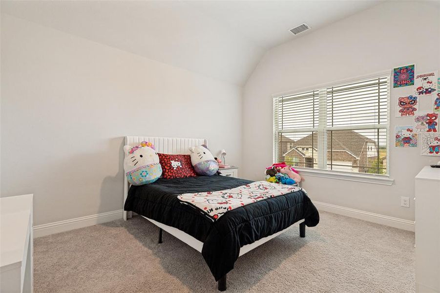 Vaulted ceiling bedroom featuring plush carpet flooring, a large window with blinds, and white baseboards