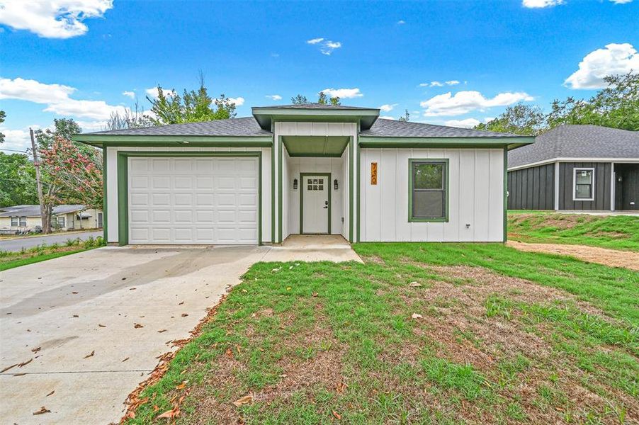 View of front of property featuring a garage and a front lawn