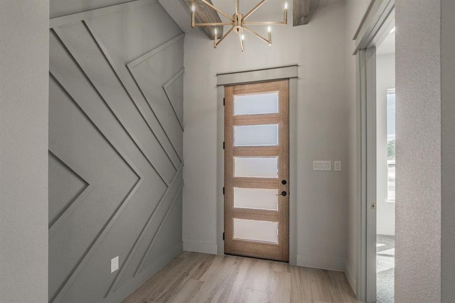 Foyer with light wood-style flooring, a chandelier, and plenty of natural light