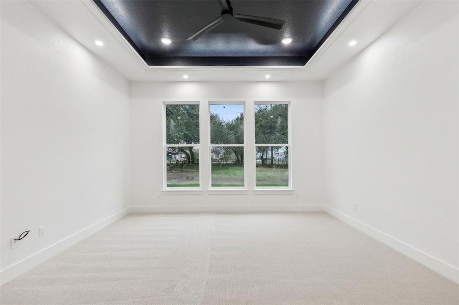 Carpeted empty room with a tray ceiling and ceiling fan