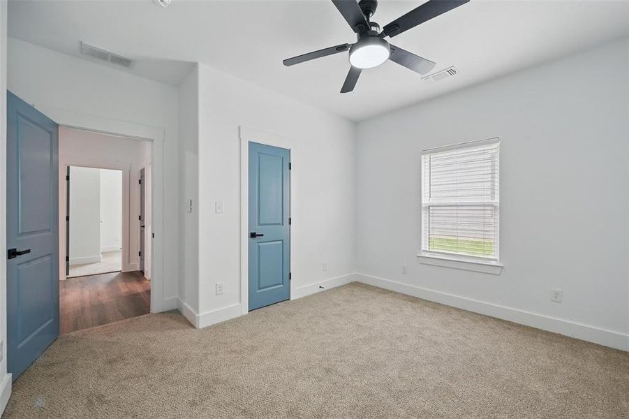 Carpeted empty room featuring ceiling fan, baseboards, and visible vents