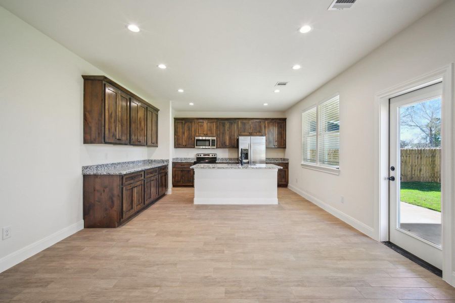 Kitchen / Dining featuring dark brown cabinets, a center island with sink, and stainless steel appliances Kitchen / Dining featuring dark brown cabinets, a center island with sink, and stainless steel appliances