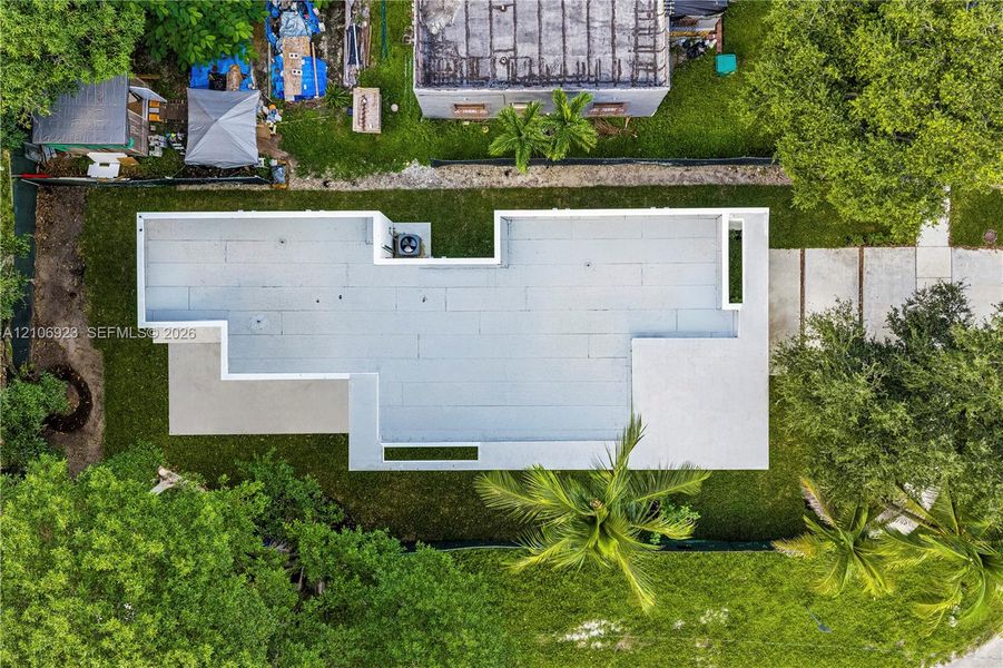 Aerial perspective of property featuring a flat roofline, concrete driveway, and established trees within the lot boundaries Aerial perspective of property featuring a flat roofline, concrete driveway, and established trees within the lot boundaries
