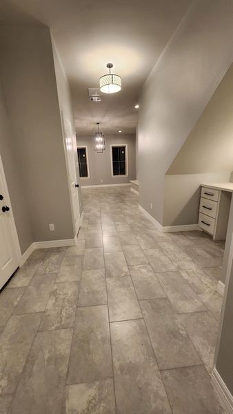 Your front entryway showcases a modern, well-lit hallway. It features contemporary light fixtures and a built-in desk area under the stairs, offering both aesthetic appeal and functionality.