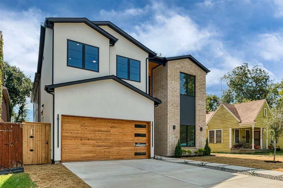 Contemporary house with driveway, stucco siding, covered porch, an attached garage, and a gate Contemporary house with driveway, stucco siding, covered porch, an attached garage, and a gate
