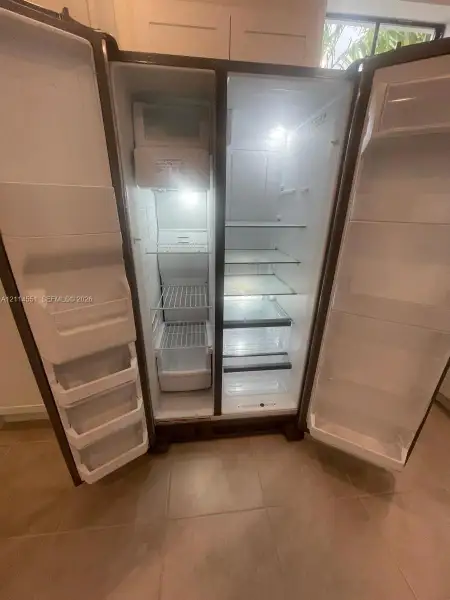 Side-by-side refrigerator featuring adjustable glass shelving, integrated door storage bins, dedicated freezer compartment, and interior lighting