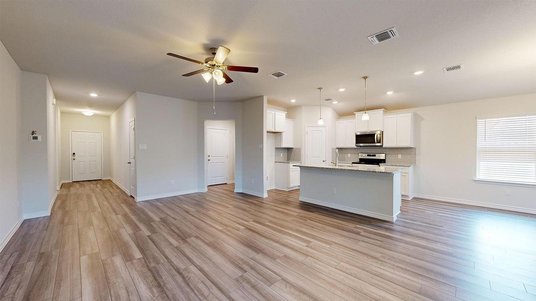 Kitchen with open floor plan, white cabinetry, a ceiling fan, and hanging light fixtures Kitchen with open floor plan, white cabinetry, a ceiling fan, and hanging light fixtures